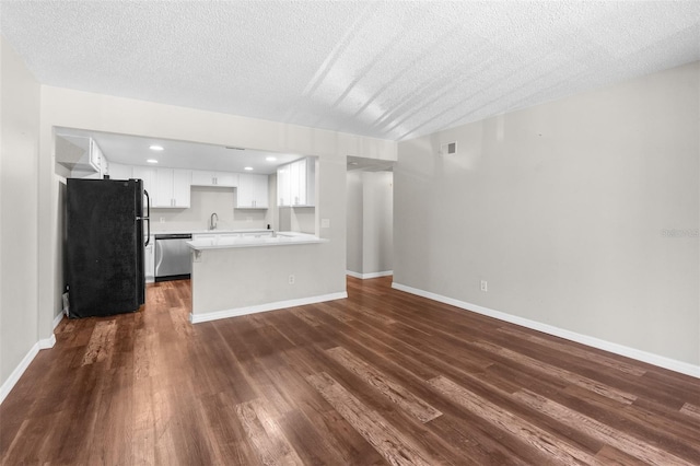 unfurnished living room featuring a textured ceiling, dark wood-type flooring, and sink