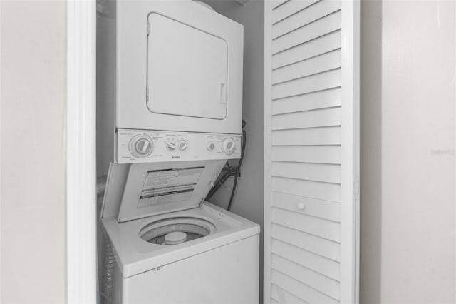 clothes washing area with stacked washing maching and dryer