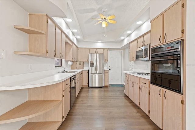 kitchen with lofted ceiling, sink, appliances with stainless steel finishes, light hardwood / wood-style floors, and light brown cabinets