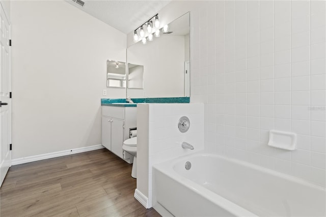 bathroom with a bathing tub, hardwood / wood-style flooring, vanity, toilet, and a textured ceiling