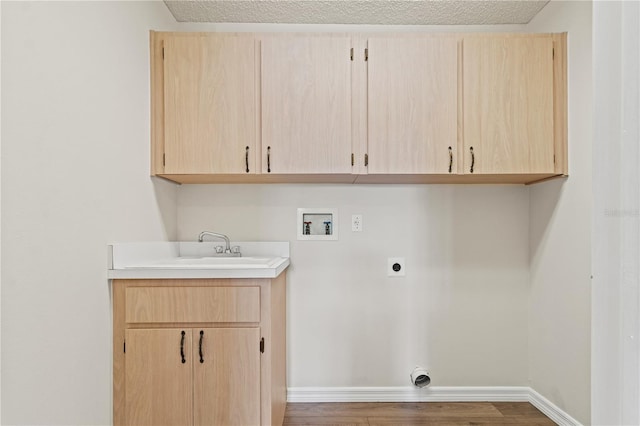 laundry room featuring sink, electric dryer hookup, hookup for a washing machine, cabinets, and a textured ceiling