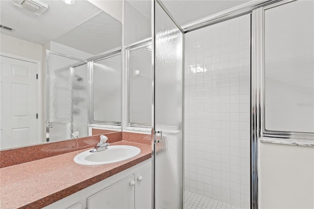 bathroom with vanity, a textured ceiling, and a shower with shower door