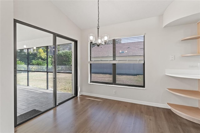 unfurnished dining area with lofted ceiling, hardwood / wood-style floors, and a chandelier