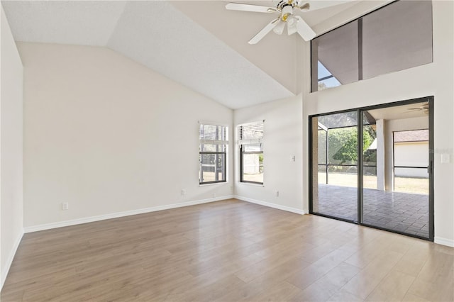 unfurnished room with ceiling fan, a healthy amount of sunlight, high vaulted ceiling, and light wood-type flooring