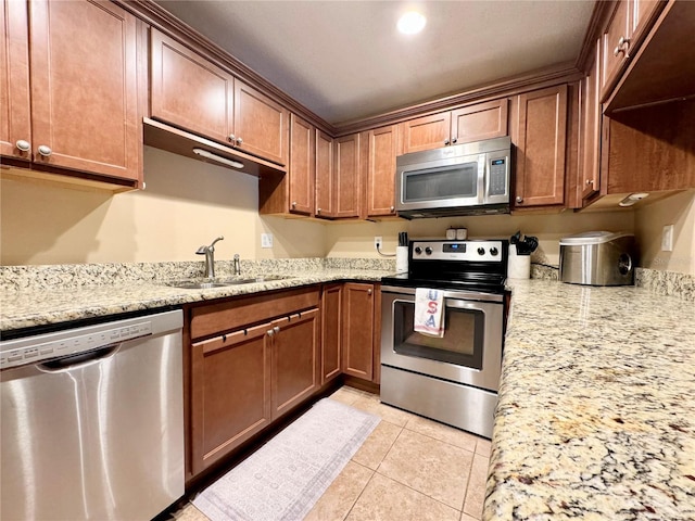 kitchen with sink, light stone countertops, appliances with stainless steel finishes, and light tile patterned flooring