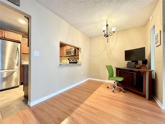 office area featuring light wood-type flooring, a textured ceiling, and an inviting chandelier