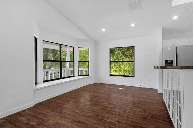 unfurnished living room featuring a textured ceiling, lofted ceiling, and dark wood-type flooring