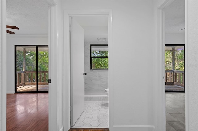 hall with tile patterned flooring, crown molding, and a textured ceiling