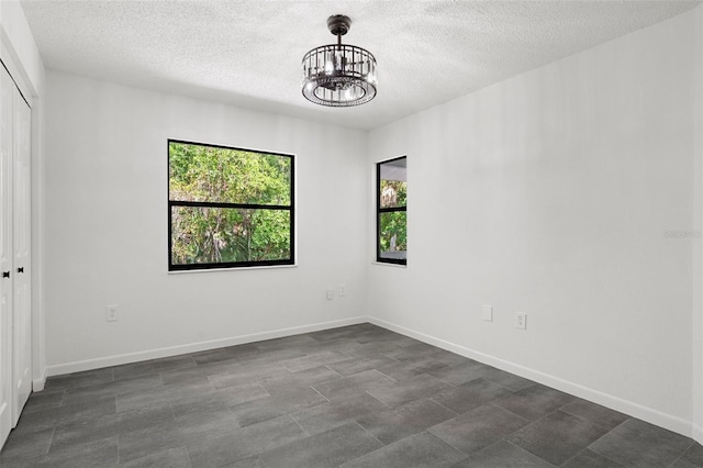 empty room featuring a chandelier and a textured ceiling