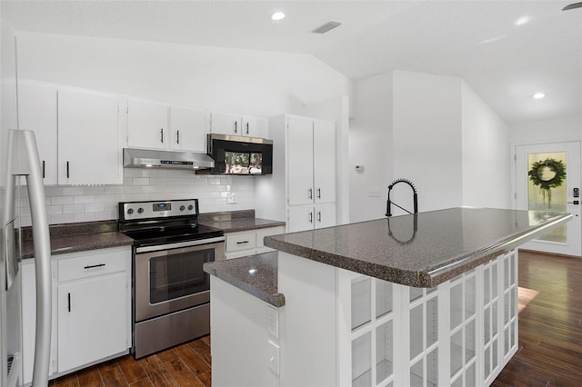 kitchen with backsplash, white cabinets, vaulted ceiling, an island with sink, and appliances with stainless steel finishes