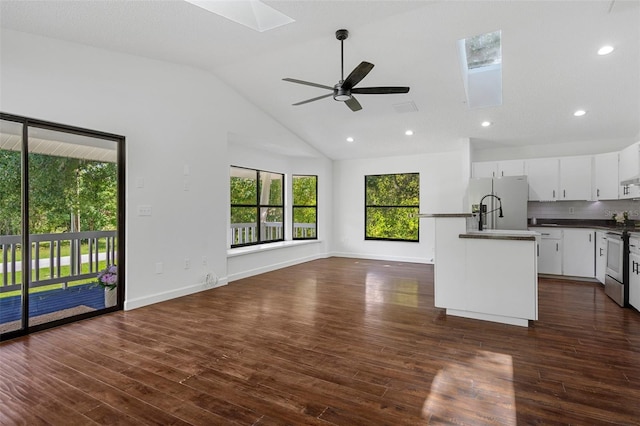 kitchen featuring white cabinets, electric stove, decorative backsplash, ceiling fan, and an island with sink