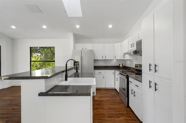 kitchen featuring stainless steel appliances, a kitchen island, a textured ceiling, decorative backsplash, and white cabinets