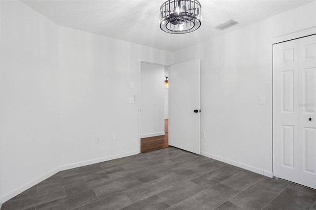 empty room featuring a textured ceiling and a notable chandelier