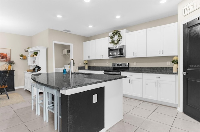 kitchen featuring light tile patterned flooring, white cabinetry, sink, a kitchen island with sink, and stainless steel appliances