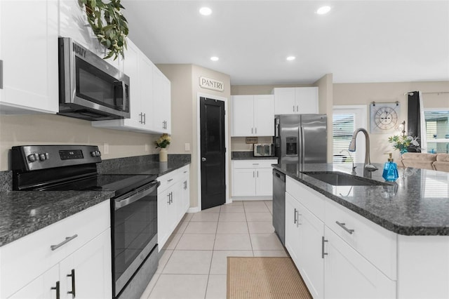 kitchen featuring light tile patterned floors, appliances with stainless steel finishes, sink, and white cabinets