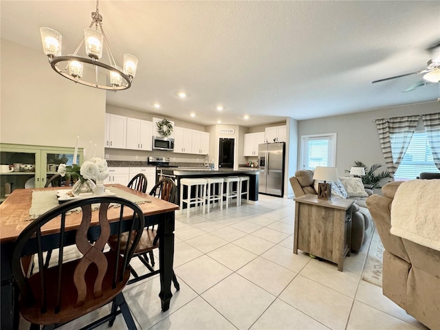 tiled dining room with ceiling fan with notable chandelier