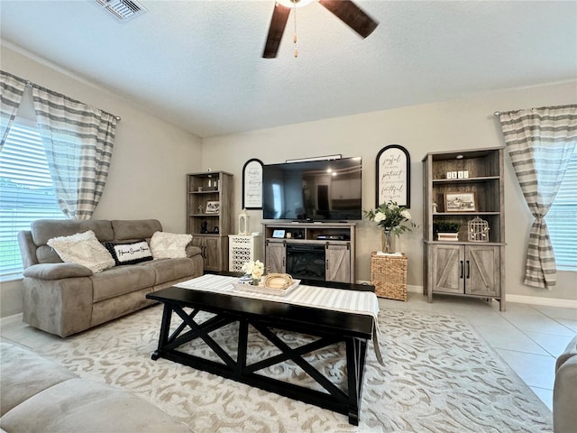 living room with light tile patterned flooring, ceiling fan, and a textured ceiling