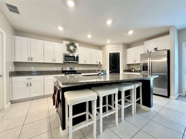 kitchen with stainless steel appliances, a kitchen island with sink, sink, and white cabinets