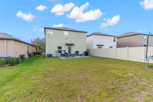 rear view of house featuring central AC, a trampoline, a yard, and a patio area