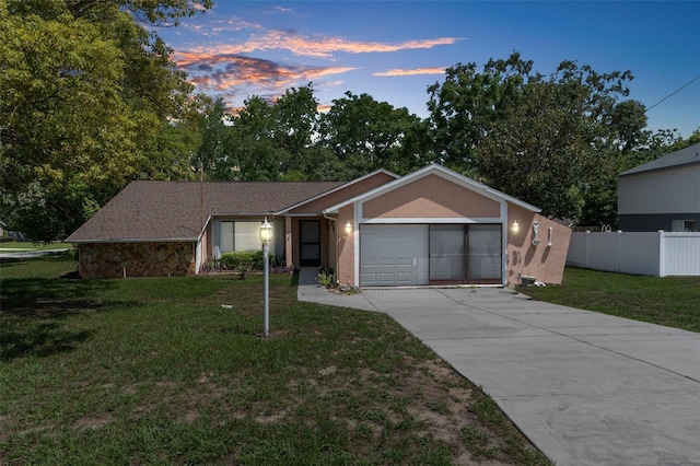 ranch-style house with a garage and a yard