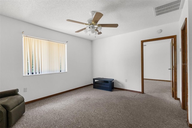 carpeted empty room with ceiling fan and a textured ceiling