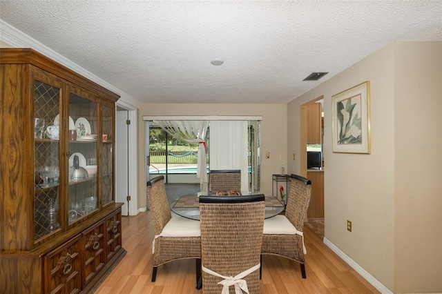 dining space with hardwood / wood-style floors and a textured ceiling