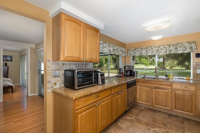 kitchen with tasteful backsplash, light hardwood / wood-style flooring, a textured ceiling, dishwasher, and sink