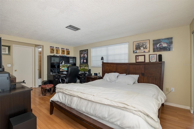 bedroom featuring a textured ceiling and light hardwood / wood-style flooring