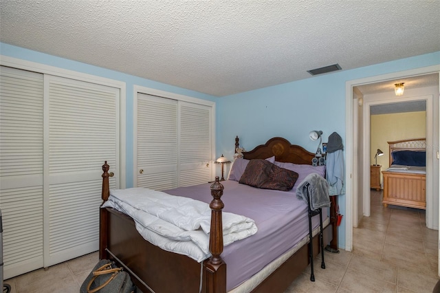 tiled bedroom with multiple closets and a textured ceiling