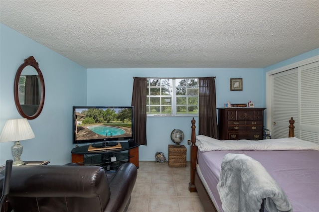 bedroom featuring a textured ceiling, light tile patterned floors, and a closet