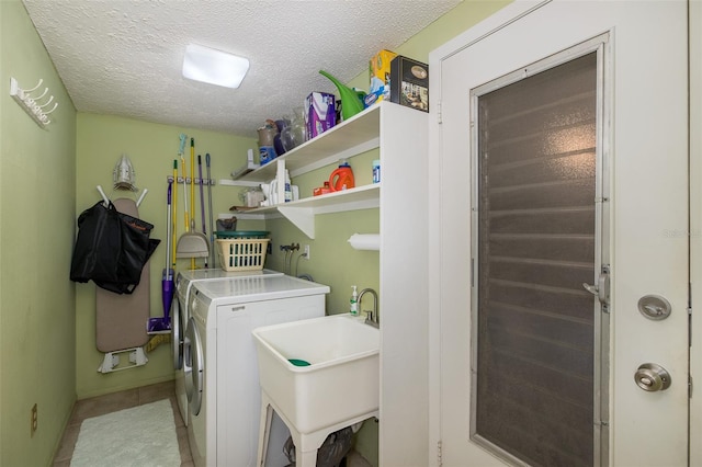 washroom featuring a textured ceiling, washer and clothes dryer, and sink