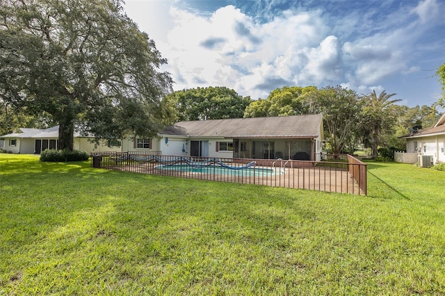 rear view of house featuring a yard, central AC unit, and a fenced in pool