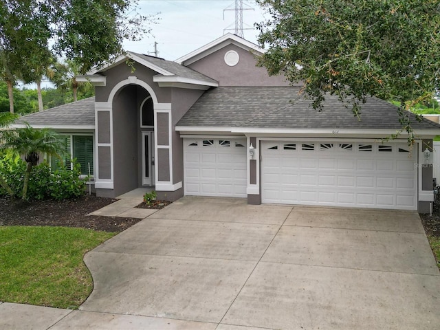 view of front of house featuring a shingled roof, concrete driveway, an attached garage, and stucco siding