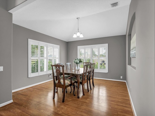 dining area with hardwood / wood-style flooring and a notable chandelier