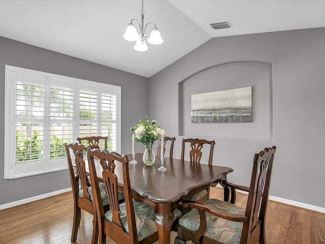 dining room featuring an inviting chandelier, lofted ceiling, and hardwood / wood-style flooring