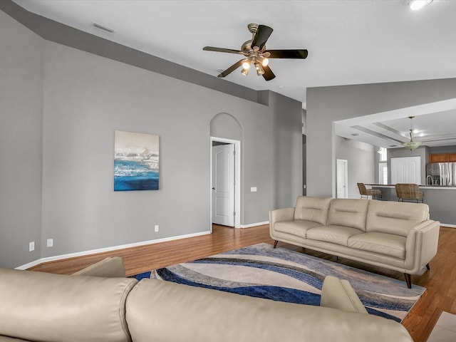 living room featuring wood-type flooring, vaulted ceiling, and ceiling fan