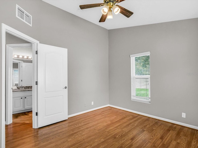 unfurnished bedroom with sink, ensuite bathroom, ceiling fan, and hardwood / wood-style floors