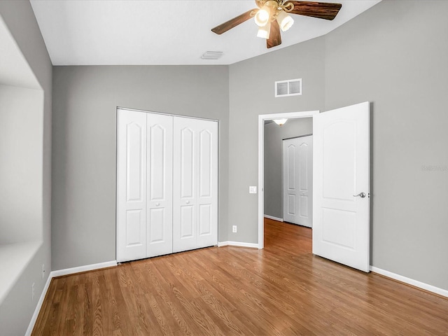 unfurnished bedroom with hardwood / wood-style flooring, vaulted ceiling, a closet, and ceiling fan