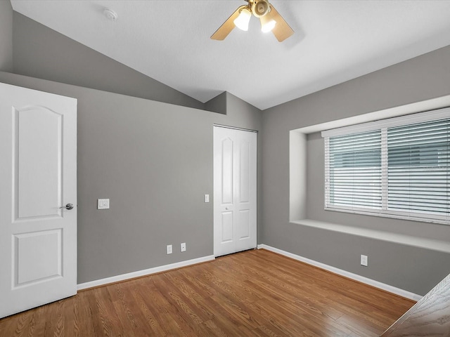 unfurnished bedroom with a closet, lofted ceiling, ceiling fan, and hardwood / wood-style floors