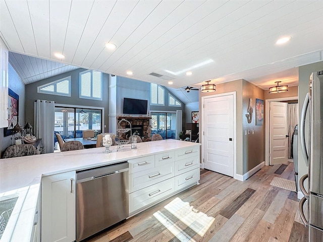 kitchen featuring plenty of natural light, appliances with stainless steel finishes, vaulted ceiling, and white cabinets