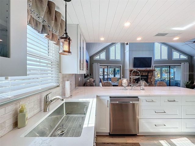 kitchen featuring sink, decorative light fixtures, dishwasher, kitchen peninsula, and white cabinets