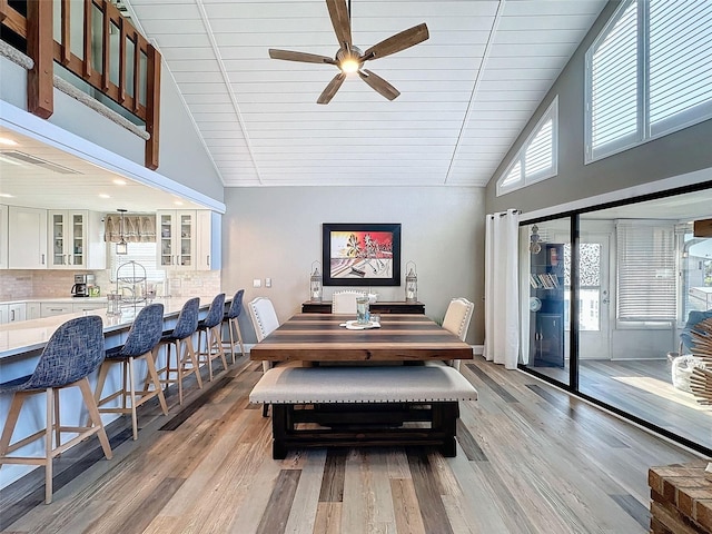 dining area featuring high vaulted ceiling, a healthy amount of sunlight, and light wood-type flooring