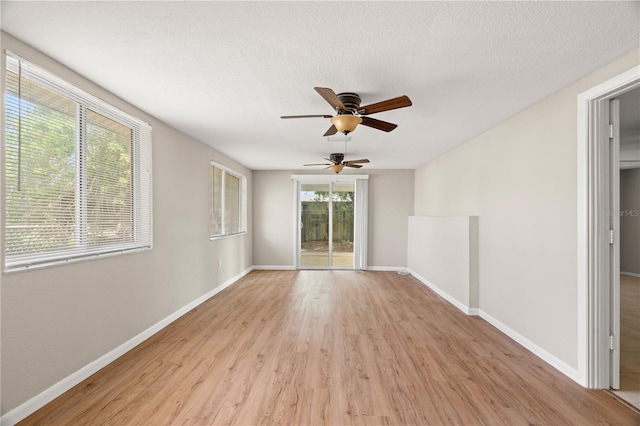 empty room featuring ceiling fan, light wood-type flooring, and a textured ceiling