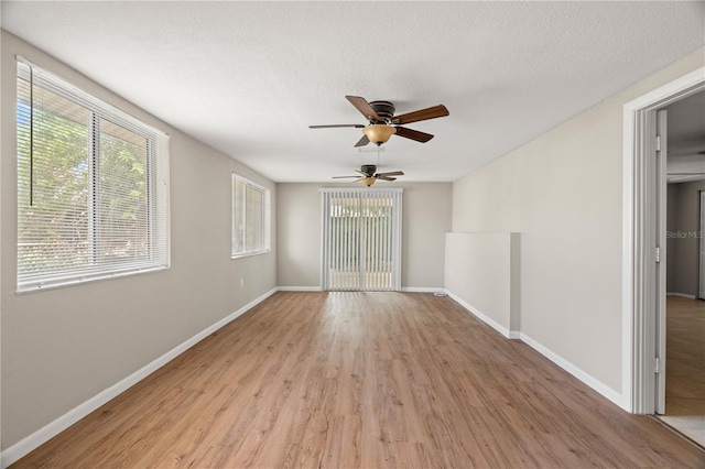 spare room featuring a healthy amount of sunlight, ceiling fan, and light hardwood / wood-style floors