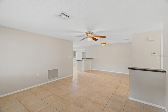 tiled empty room with ceiling fan and a textured ceiling