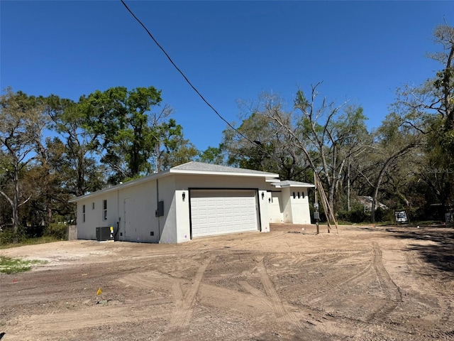 exterior space featuring central air condition unit, a garage, driveway, and stucco siding