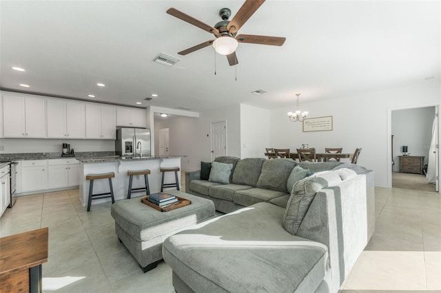 tiled living room featuring ceiling fan with notable chandelier