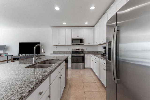 kitchen with stone counters, light tile patterned flooring, appliances with stainless steel finishes, white cabinetry, and sink