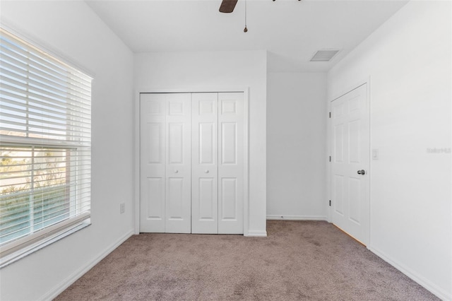 unfurnished bedroom with light colored carpet, ceiling fan, and a closet