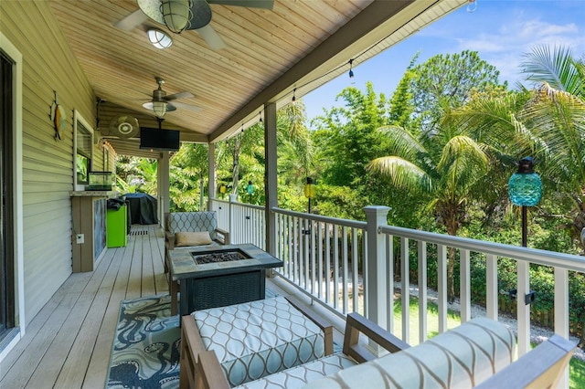 deck with ceiling fan and an outdoor fire pit